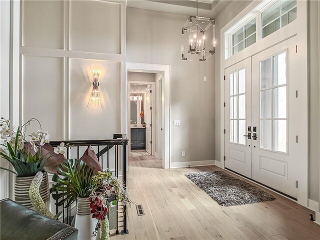 16724 Hayes St, Overland Park, KS 66085 - entryway with french doors, a towering ceiling, a chandelier, light wood-type flooring, and baseboards