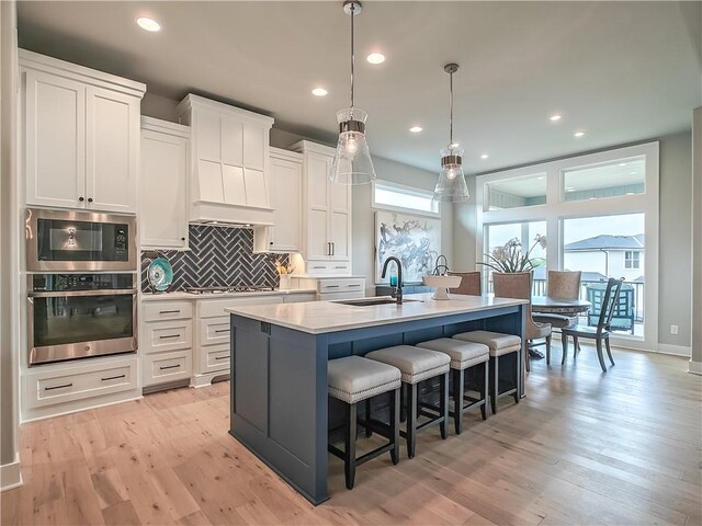 16724 Hayes St, Overland Park, KS 66085 - kitchen featuring stainless steel appliances, a sink, an island with sink, tasteful backsplash, and white cabinets