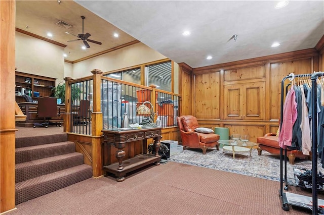 interior space with ceiling fan, carpet flooring, wooden walls, and crown molding