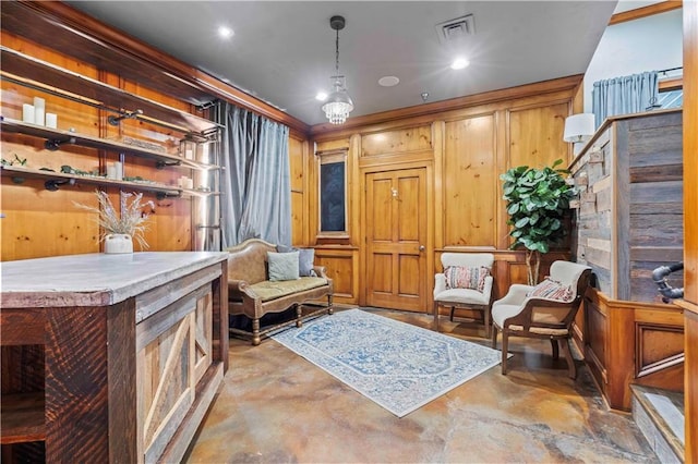 living area featuring wood walls, crown molding, and concrete floors