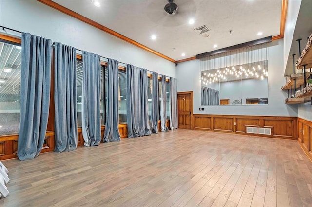 interior space featuring light hardwood / wood-style floors, a towering ceiling, and ornamental molding