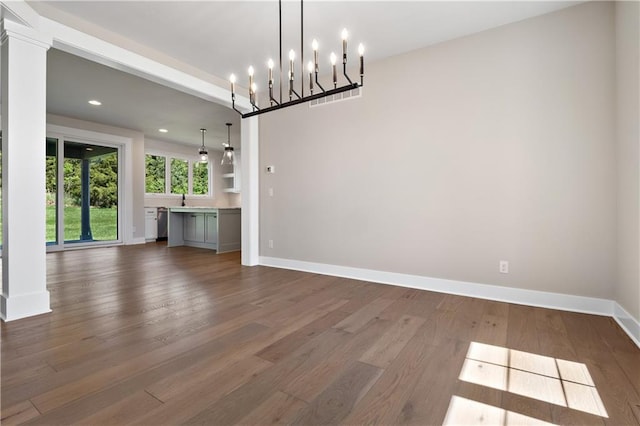 unfurnished living room with a chandelier and dark wood-type flooring