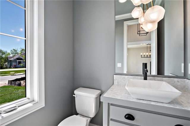 bathroom with large vanity, a notable chandelier, toilet, and ornamental molding