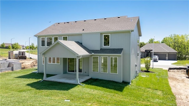 rear view of house featuring a garage, a yard, and a patio