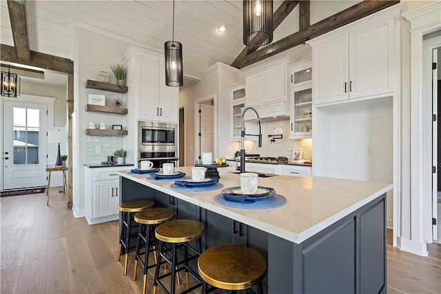 kitchen featuring white cabinetry, a center island with sink, and pendant lighting