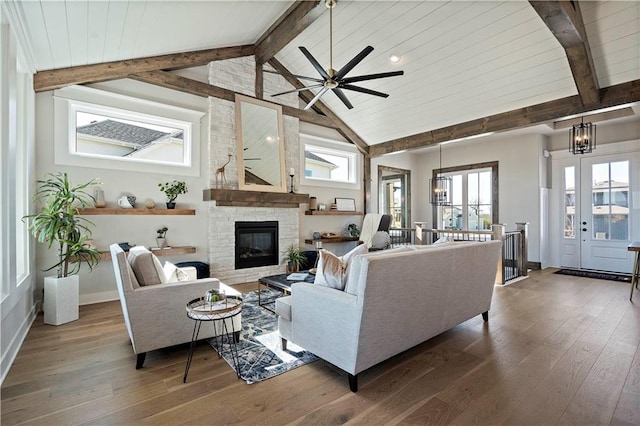 living room with dark hardwood / wood-style floors, ceiling fan, beamed ceiling, a fireplace, and high vaulted ceiling