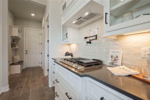 kitchen with tasteful backsplash, dark wood-type flooring, premium range hood, stainless steel gas stovetop, and white cabinets