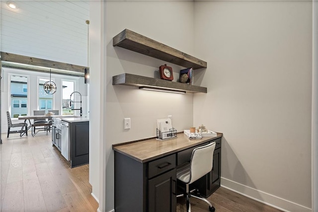 office featuring a chandelier, a towering ceiling, and light hardwood / wood-style flooring