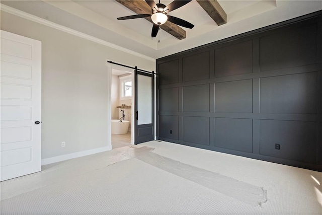 spare room with a barn door, beam ceiling, a tray ceiling, and ceiling fan