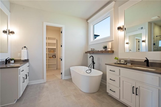 bathroom featuring dual sinks, a washtub, tile floors, and vanity with extensive cabinet space