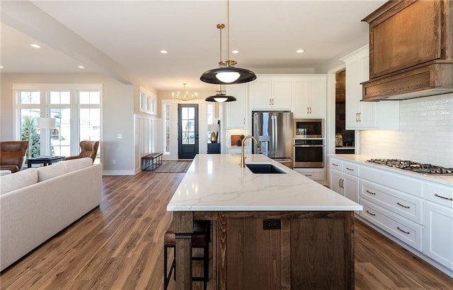 kitchen featuring white cabinets, light stone countertops, a kitchen island with sink, dark wood-type flooring, and stainless steel appliances