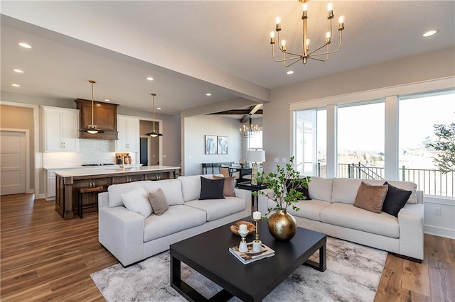 living room featuring an inviting chandelier, beam ceiling, and hardwood / wood-style flooring