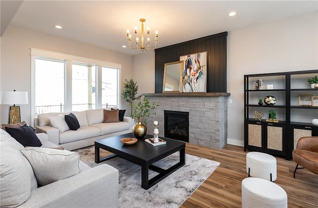 living room featuring wood-type flooring, a chandelier, and a fireplace