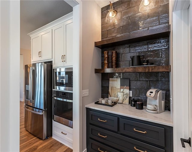 kitchen featuring white cabinetry, tasteful backsplash, appliances with stainless steel finishes, and light hardwood / wood-style flooring