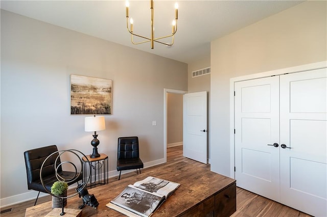 sitting room with wood-type flooring and an inviting chandelier