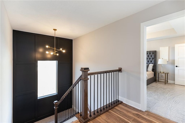 stairs with hardwood / wood-style flooring and an inviting chandelier