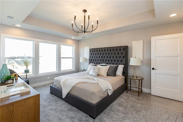 carpeted bedroom featuring a chandelier and a tray ceiling