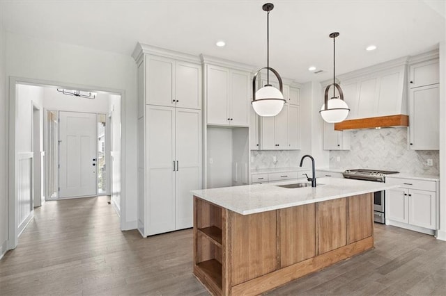 kitchen featuring white cabinetry, stainless steel range with gas cooktop, a center island with sink, and sink