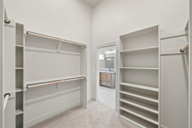 walk in closet featuring light colored carpet and sink