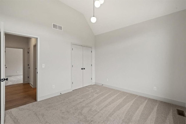 unfurnished bedroom with carpet floors, a closet, and lofted ceiling