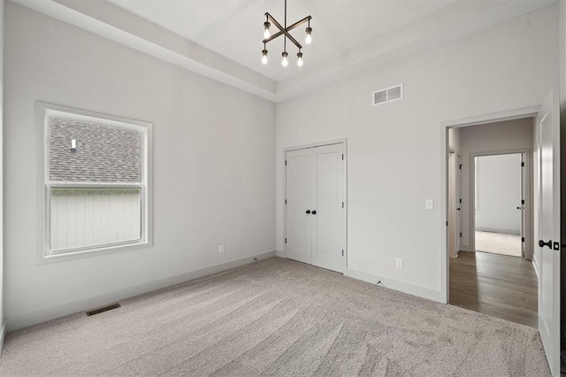 unfurnished bedroom featuring a closet, carpet floors, and a notable chandelier