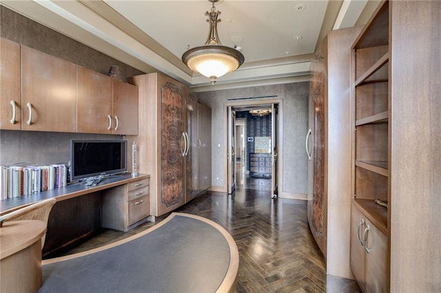 interior space with pendant lighting, dark parquet flooring, built in desk, and a raised ceiling