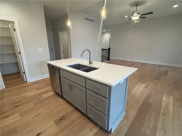 kitchen with pendant lighting, dishwasher, a center island with sink, sink, and light hardwood / wood-style floors