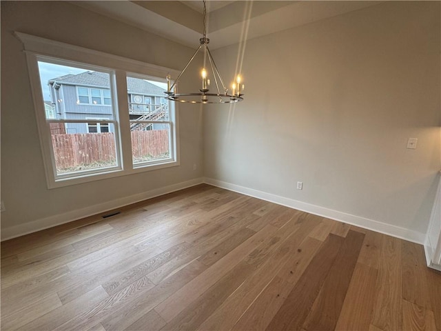 unfurnished dining area featuring a chandelier and hardwood / wood-style flooring