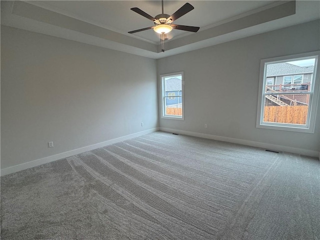 unfurnished room featuring a tray ceiling, ceiling fan, and carpet flooring