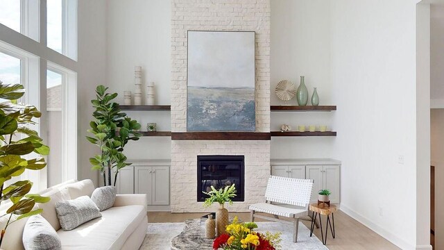 16743 S Hall St, Olathe, KS 66062 - living area with light wood-type flooring, a high ceiling, baseboards, and a brick fireplace