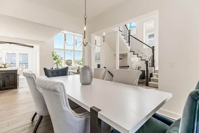 16743 S Hall St, Olathe, KS 66062 - dining space with light wood-style flooring, a high ceiling, an inviting chandelier, and stairs