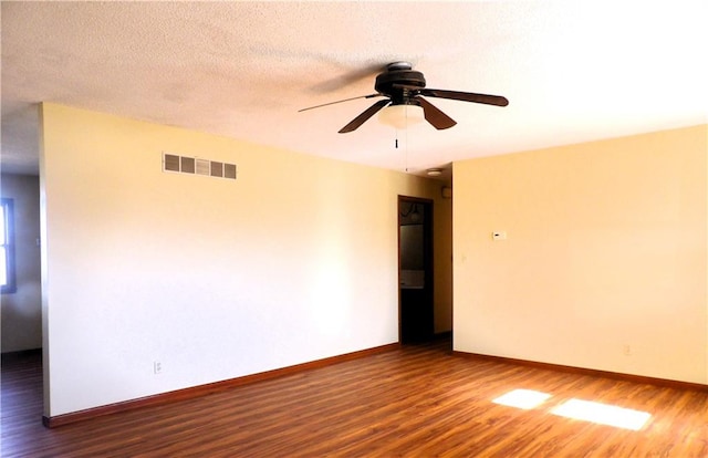 empty room with a textured ceiling, ceiling fan, and dark wood-type flooring