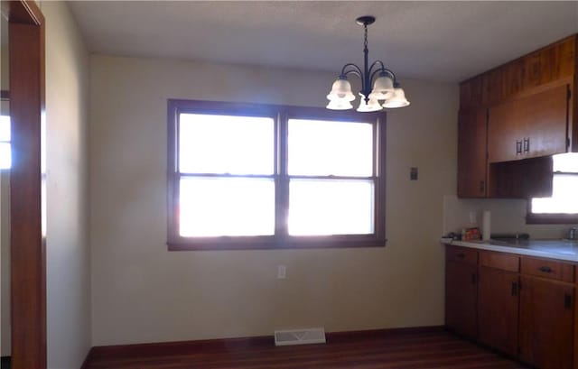 kitchen with dark hardwood / wood-style flooring, a wealth of natural light, a chandelier, and decorative light fixtures