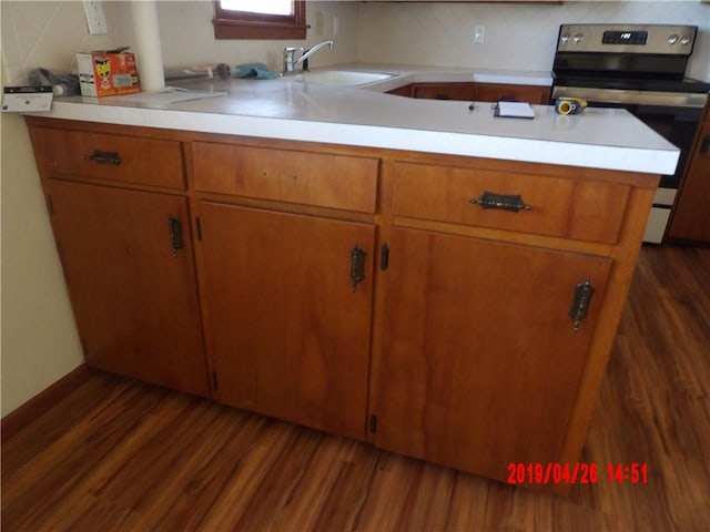 kitchen with kitchen peninsula, dark hardwood / wood-style flooring, stainless steel range with electric stovetop, and sink