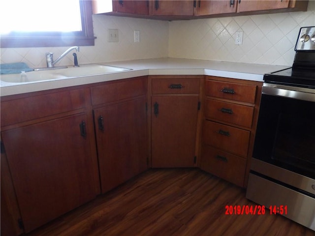 kitchen featuring dark hardwood / wood-style flooring, backsplash, sink, and stainless steel electric range