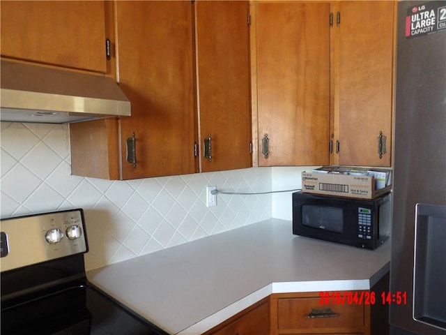 kitchen with backsplash, range, and wall chimney range hood