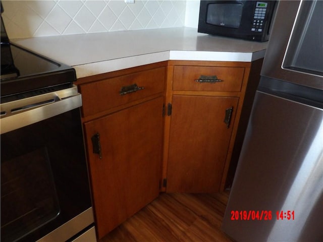 kitchen with dark hardwood / wood-style flooring and appliances with stainless steel finishes