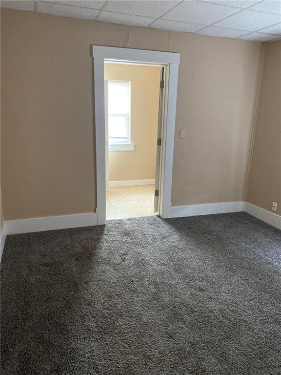 carpeted empty room featuring a paneled ceiling