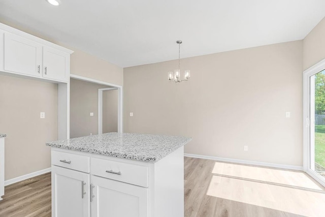 kitchen with pendant lighting, white cabinets, light wood-style flooring, and light stone countertops