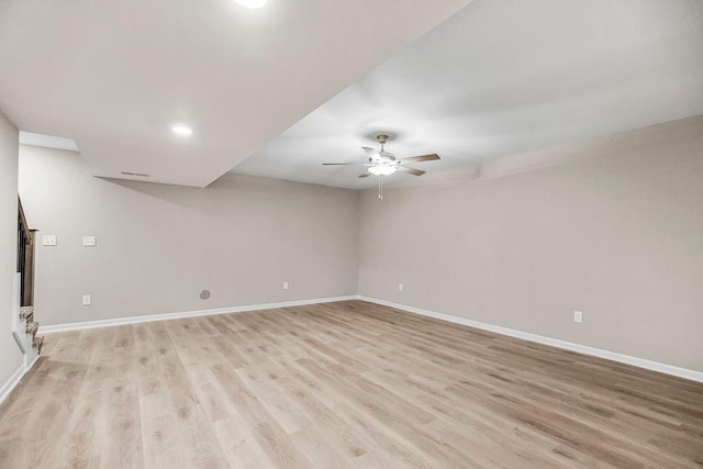 spare room featuring light wood finished floors, ceiling fan, and baseboards