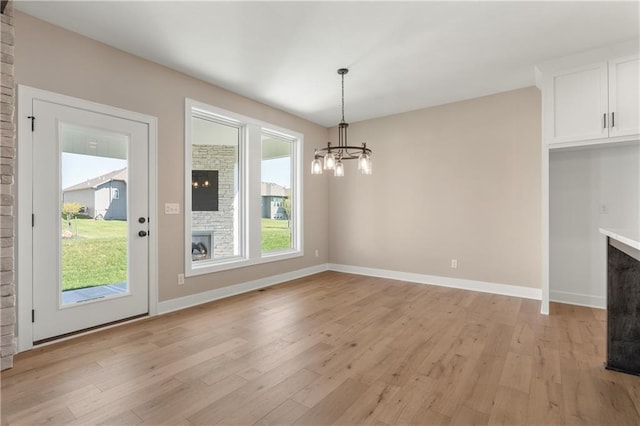 unfurnished dining area featuring light wood-type flooring and an inviting chandelier