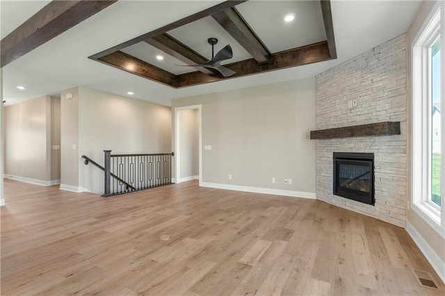 unfurnished living room featuring beamed ceiling, light hardwood / wood-style floors, ceiling fan, and a fireplace