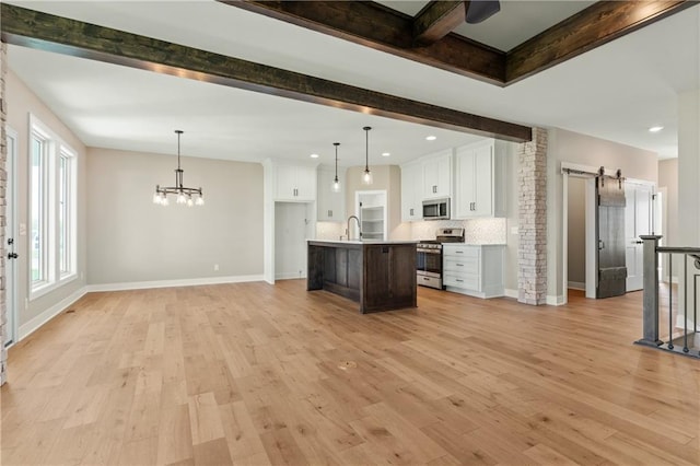 kitchen featuring stainless steel appliances, tasteful backsplash, an island with sink, white cabinetry, and light wood-type flooring