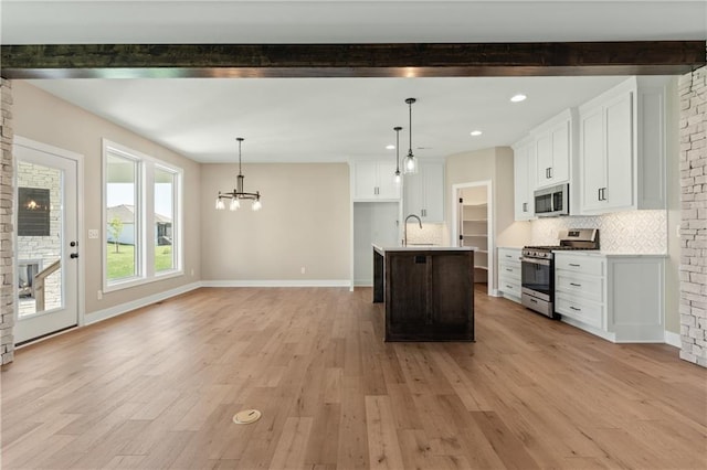 kitchen featuring tasteful backsplash, appliances with stainless steel finishes, white cabinetry, and light wood-type flooring