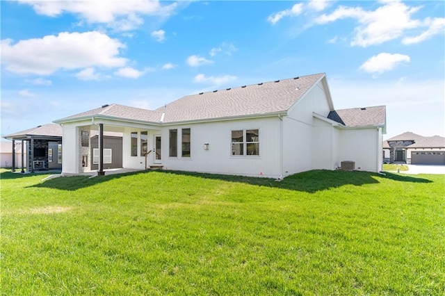 rear view of property with central AC and a lawn