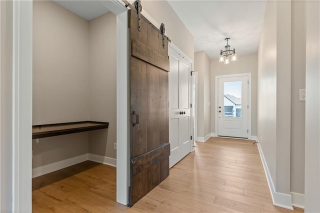 entryway featuring an inviting chandelier, a barn door, and light hardwood / wood-style floors