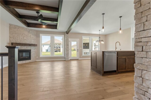 kitchen featuring pendant lighting, a fireplace, light wood-type flooring, beam ceiling, and stainless steel dishwasher