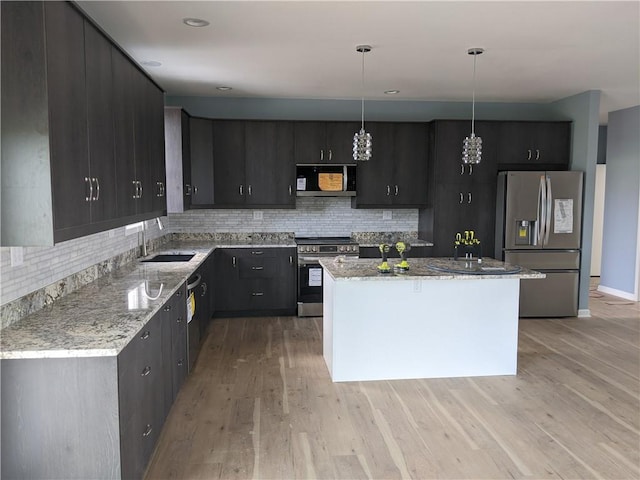 kitchen featuring hanging light fixtures, light hardwood / wood-style flooring, stainless steel appliances, a center island, and decorative backsplash