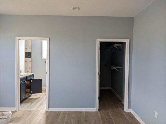 bedroom with a closet, a walk in closet, light wood-type flooring, and ensuite bath