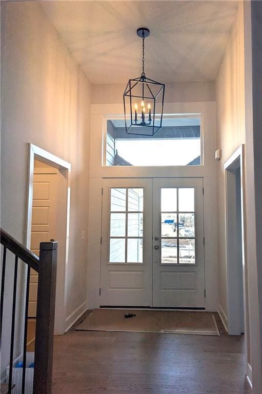 doorway with dark wood-type flooring, an inviting chandelier, french doors, and a high ceiling